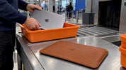 Braunes MacBook-Sleeve auf einem Tablett an der Flughafensicherheit